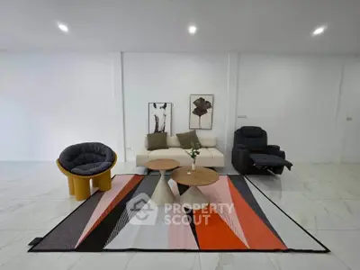 Modern living room with stylish furniture and vibrant rug in a spacious interior.