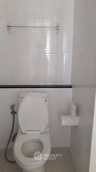 Modern bathroom with white tiles and toilet in a minimalist design.