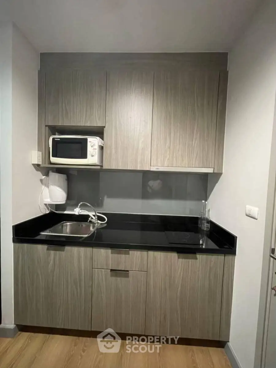 Modern compact kitchen with sleek cabinetry and built-in microwave, ideal for urban living.