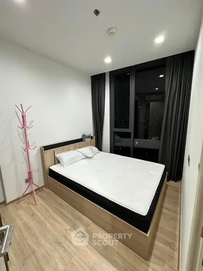 Modern bedroom with large window and stylish wooden flooring