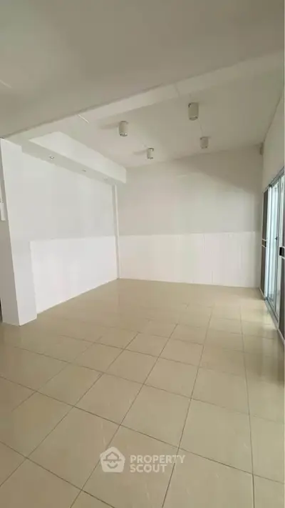 Spacious empty room with tiled flooring and large windows, perfect for customization.
