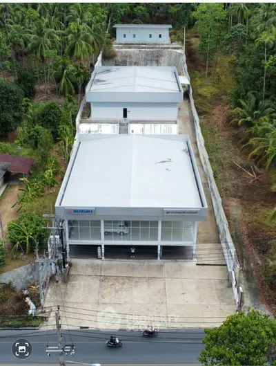 Aerial view of commercial property with spacious parking and lush surroundings, ideal for business opportunities.
