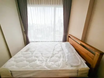 Cozy bedroom with large window offering city view, featuring a new mattress and wooden bed frame.