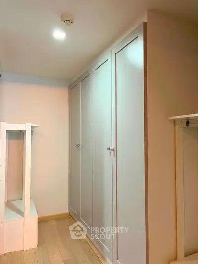 Spacious storage area with modern built-in wardrobes and wooden flooring