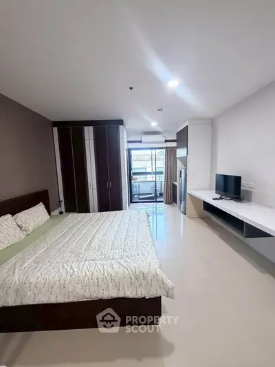 Spacious modern bedroom with balcony access and sleek furnishings in a contemporary apartment.