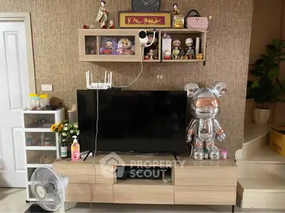 Charming living room with modern TV setup and decorative shelving, perfect for cozy family gatherings.