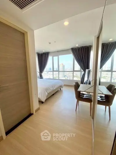 Spacious bedroom with large windows offering stunning city views, modern furnishings, and elegant decor.