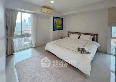 Spacious bedroom with city view and modern decor in high-rise apartment.