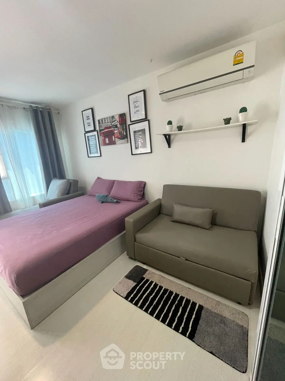 Cozy bedroom with modern decor and air conditioning, featuring a comfortable bed and stylish sofa.