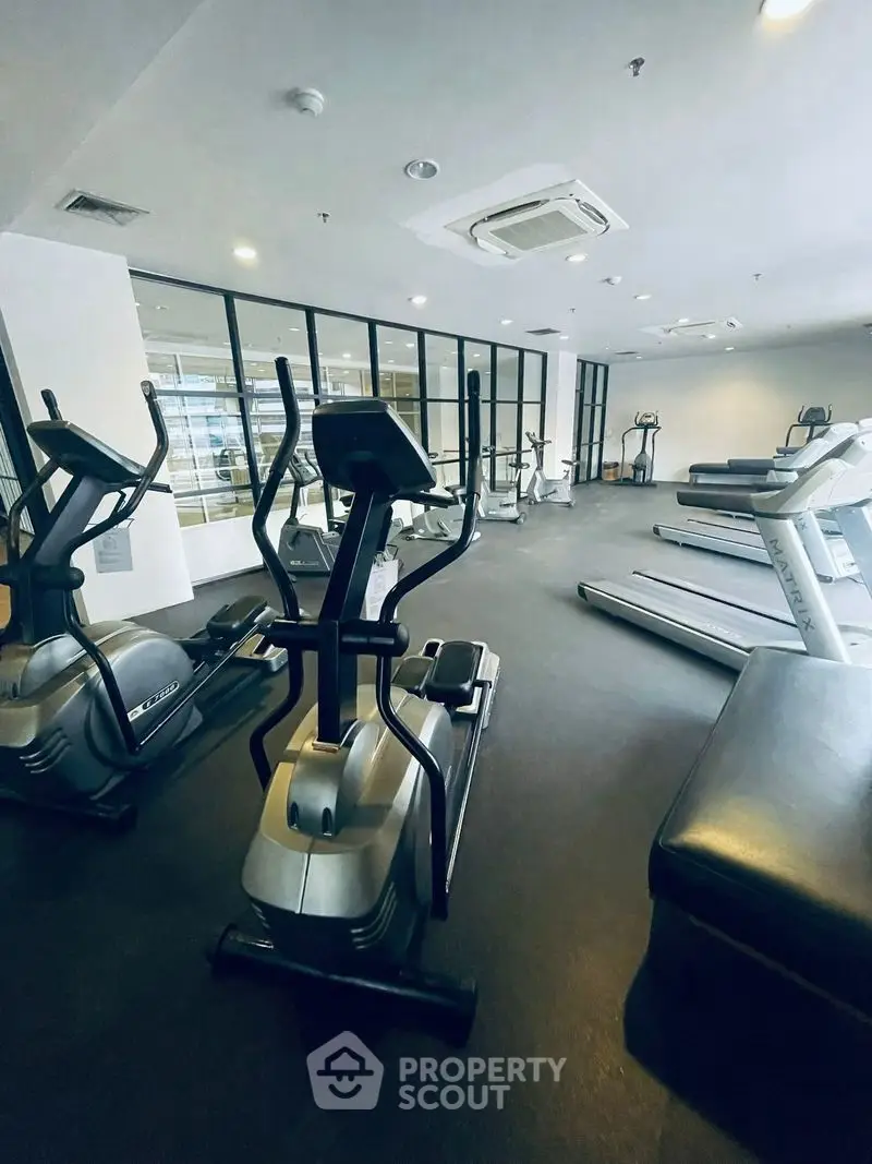 Modern gym with state-of-the-art fitness equipment and large windows for natural light.