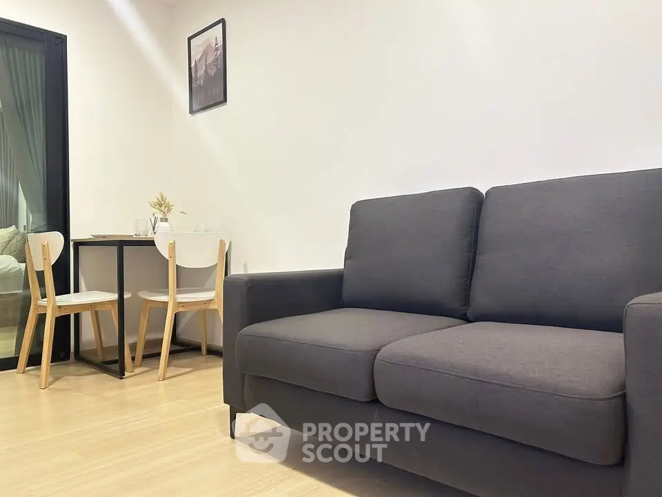 Modern living room with sleek gray sofa and cozy dining area in stylish apartment.