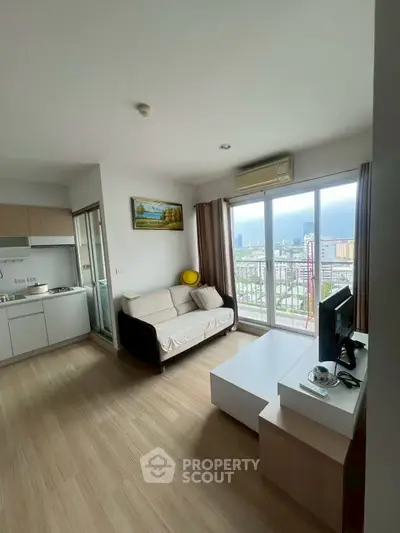 Modern living room with city view, featuring sleek furniture and open kitchen layout.