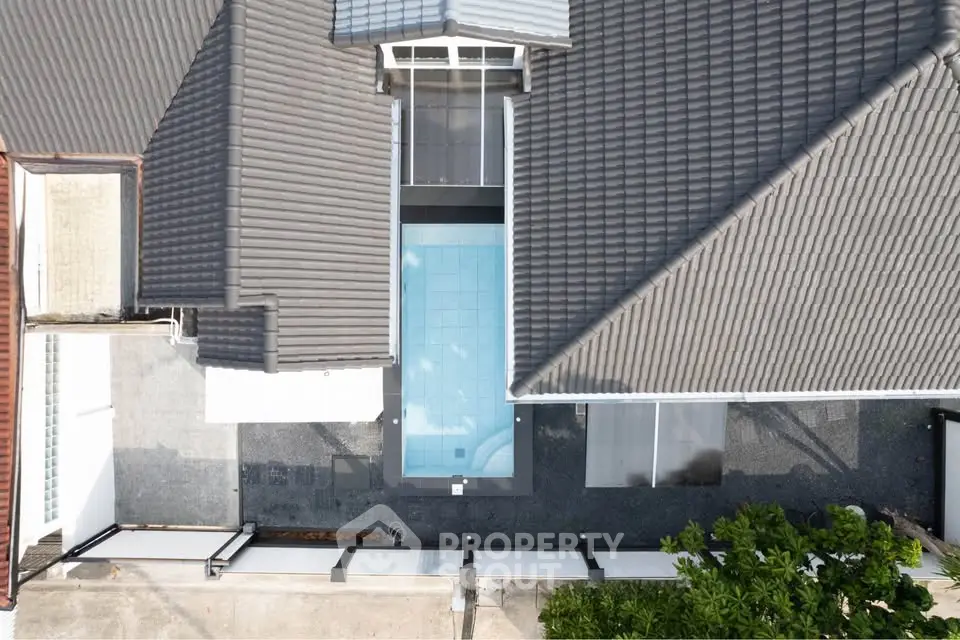 Aerial view of a modern house with a sleek rooftop and a central swimming pool.
