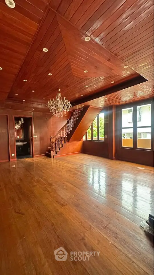 Spacious wooden interior with elegant chandelier and staircase, perfect for luxurious living.