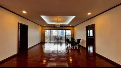 Spacious living room with elegant chandelier and city view balcony.