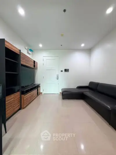 Modern living room with sleek black sofa and built-in wooden entertainment unit.