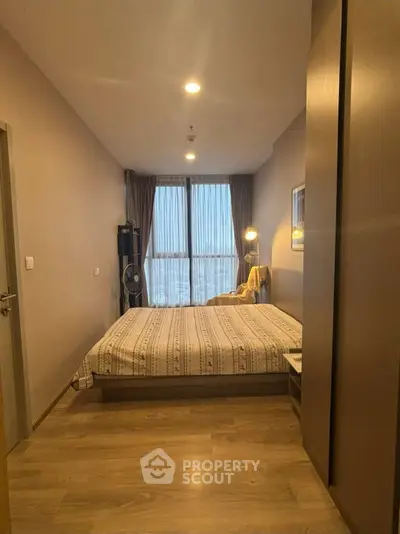 Cozy bedroom with large window and modern decor in a stylish apartment.