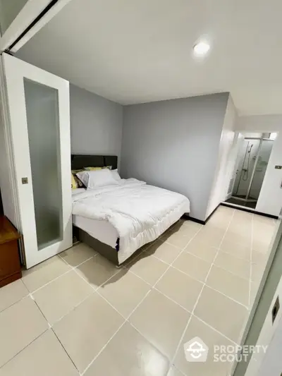 Modern minimalist bedroom with ensuite bathroom and sleek tile flooring.