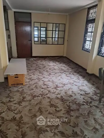 Spacious room with patterned carpet and large windows for natural light.