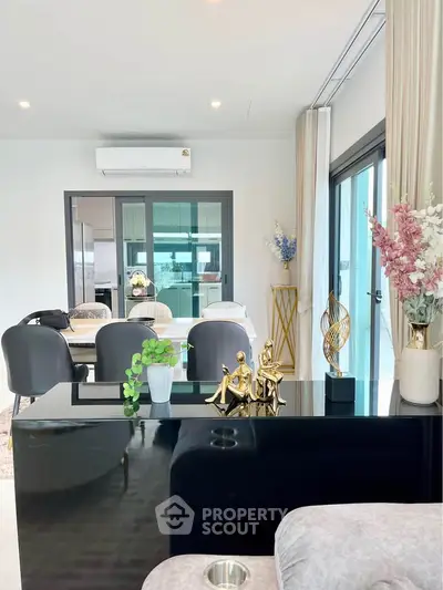 Modern living room with elegant decor and dining area, featuring large windows and stylish furniture.