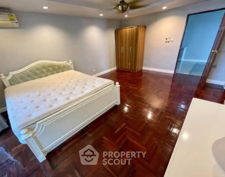 Spacious bedroom with elegant wooden flooring and stylish furniture