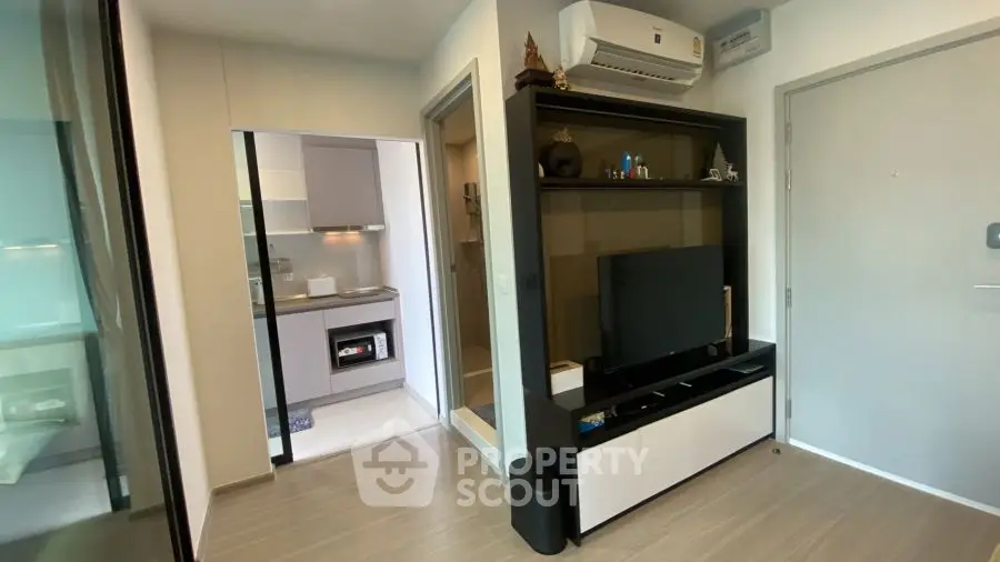 Modern living room with sleek TV unit and view into contemporary kitchen