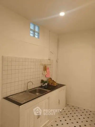 Charming kitchen with white tile backsplash and sleek stainless steel sink