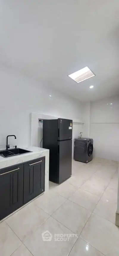 Spacious modern kitchen with sleek black appliances and ample storage space.