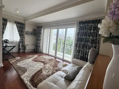 Elegant living room with large windows and stylish decor, featuring a cozy sofa and plush rug.