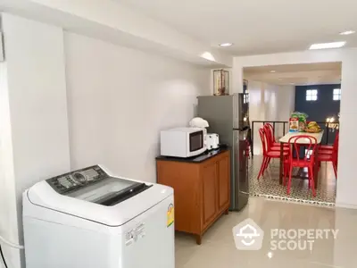 Modern kitchen with washing machine and dining area, featuring sleek appliances and stylish decor.