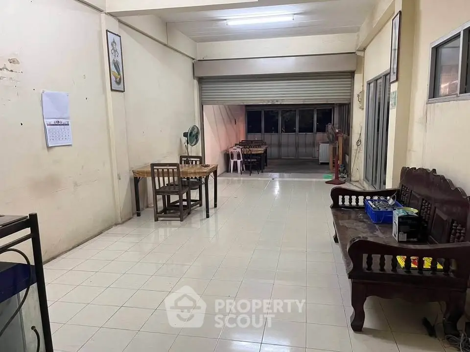 Spacious open-plan living area with tiled flooring and wooden furniture, ideal for versatile use.