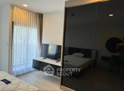 Modern bedroom with sleek black wardrobe and large window offering natural light.