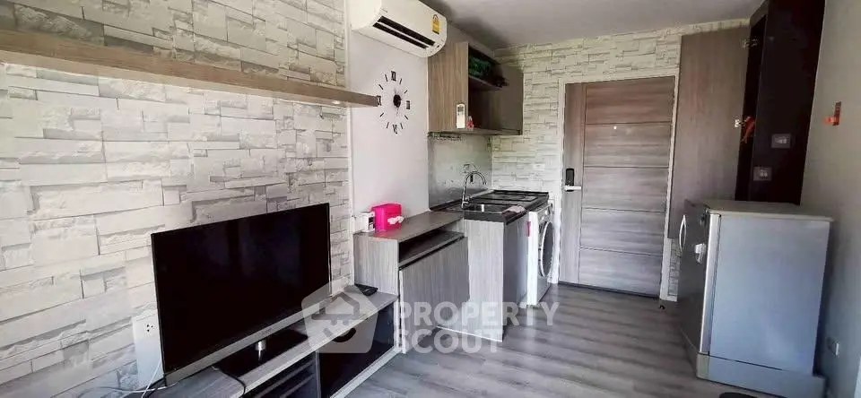 Modern compact living room with stylish decor and integrated kitchen appliances.