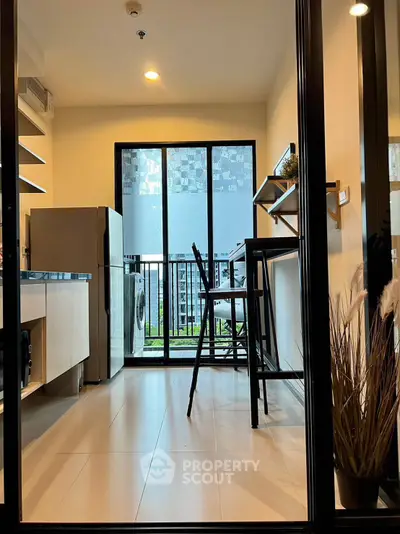 Modern kitchen with balcony view, featuring sleek appliances and stylish bar seating.