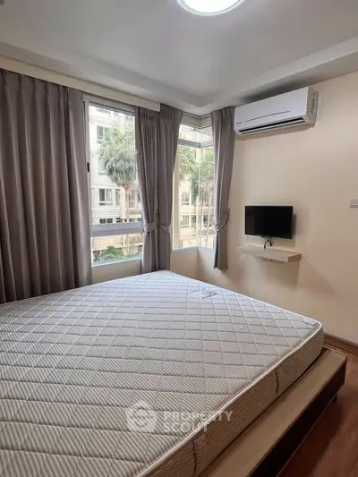 Cozy bedroom with large windows and air conditioning in modern apartment