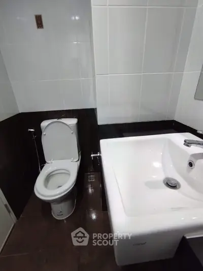 Modern bathroom with sleek white fixtures and dark tile accents