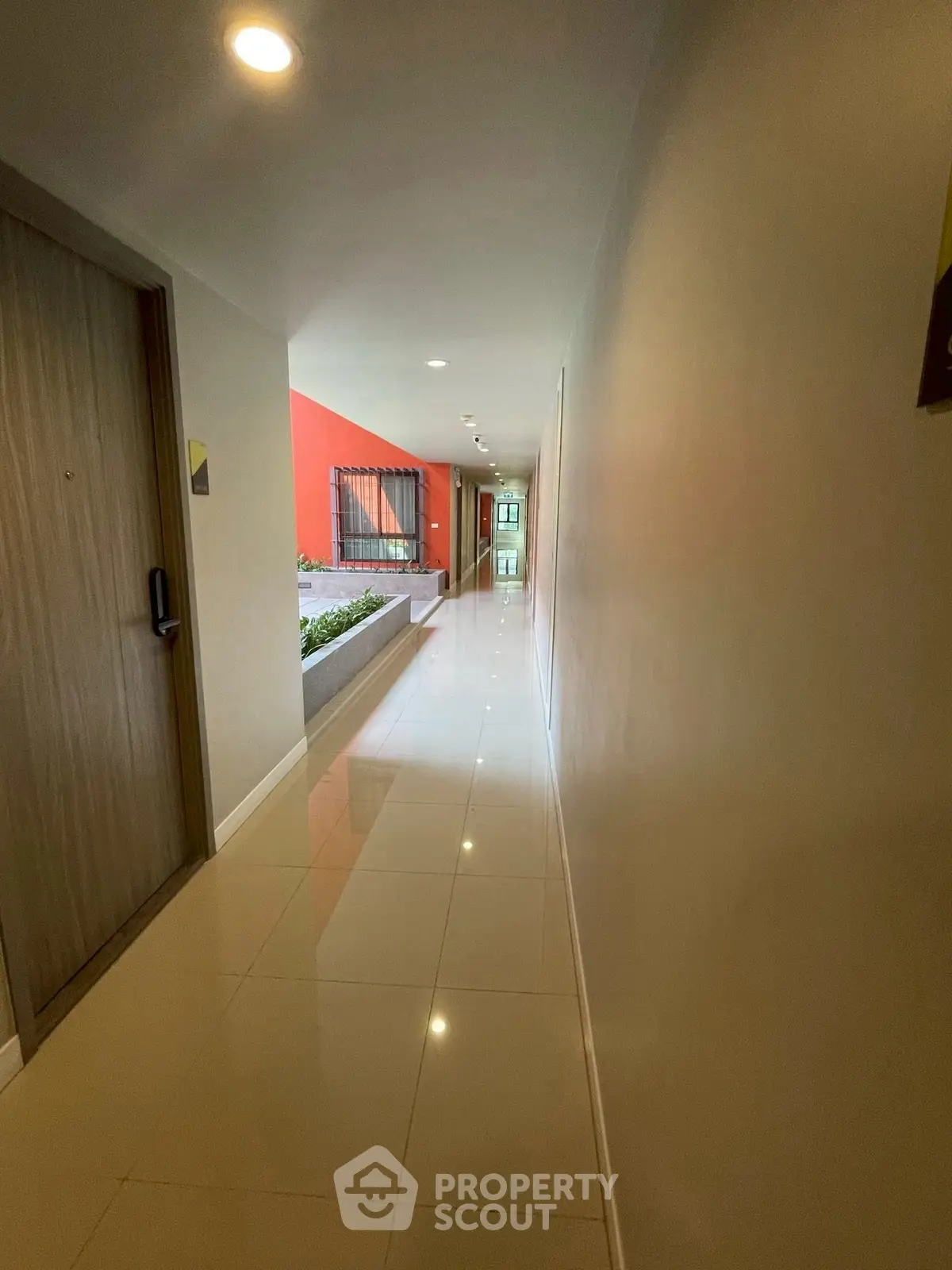 Modern apartment corridor with sleek tile flooring and vibrant red accent wall.