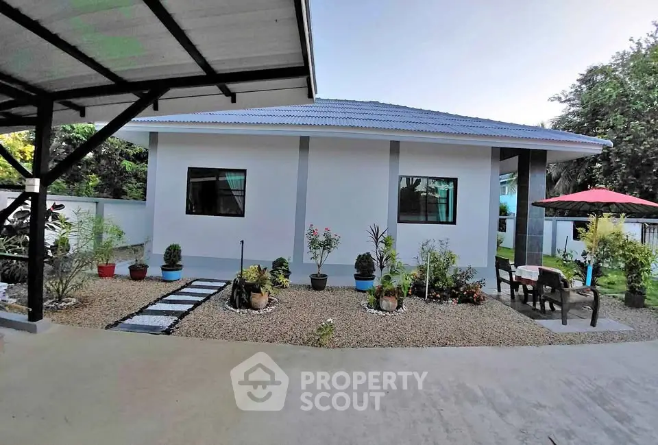 Charming single-story home with landscaped garden and outdoor seating area, perfect for relaxation.