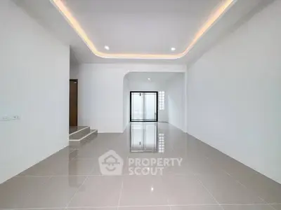 Spacious modern living room with sleek tile flooring and elegant ceiling lighting.