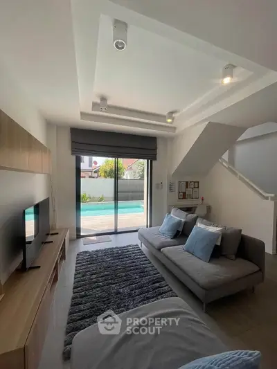 Modern living room with pool view, featuring sleek furniture and stylish decor in a bright, open space.