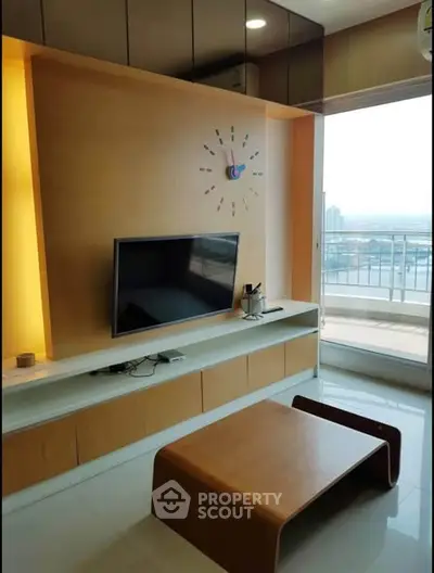 Modern living room with wall-mounted TV and balcony view in high-rise apartment.