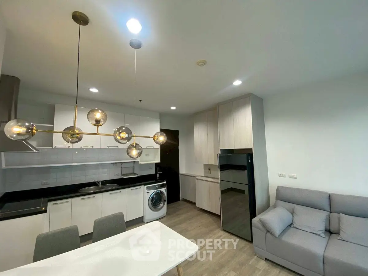 Modern kitchen with sleek design, featuring washing machine and stylish lighting.
