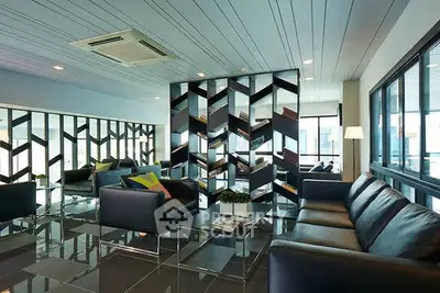 Modern living room with stylish mirrored wall and sleek black sofas.