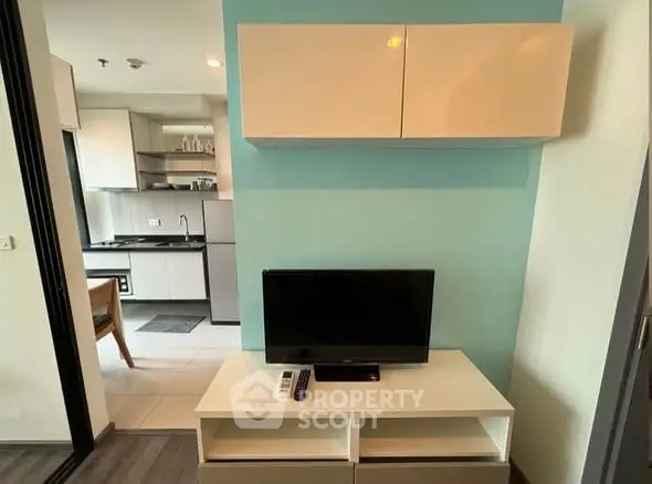 Modern apartment interior with TV, stylish kitchen, and sleek storage solutions.