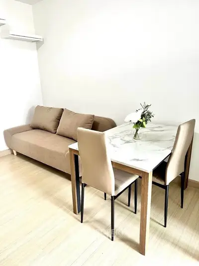 Modern living room with stylish sofa and elegant dining table in a bright, minimalist setting.