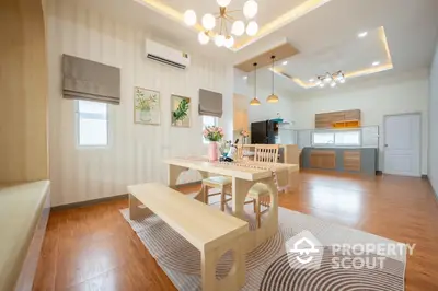 Spacious modern living room seamlessly connects to an open layout kitchen, featuring elegant lighting and hardwood floors.