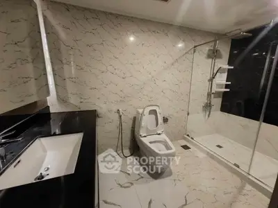 Luxurious modern bathroom with marble tiles and glass shower enclosure