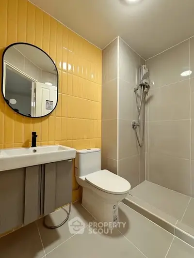 Modern bathroom with sleek shower, round mirror, and stylish sink in contemporary design.