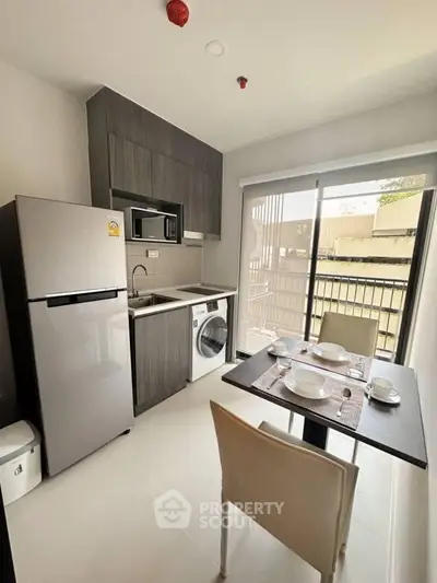 Modern compact kitchen with dining area, featuring fridge, microwave, and washing machine.