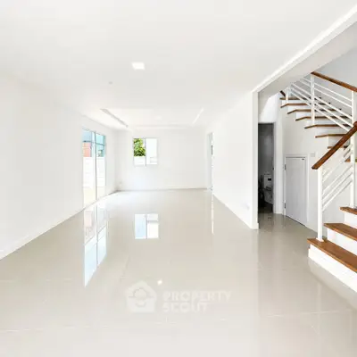 Spacious modern living room with glossy tile flooring and elegant staircase in a bright open layout.